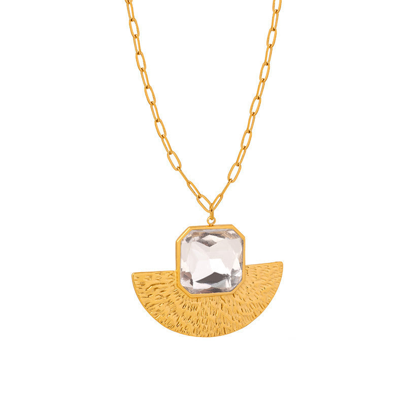 Gold chain necklace with a textured semi-circle pendant and a large clear square gemstone