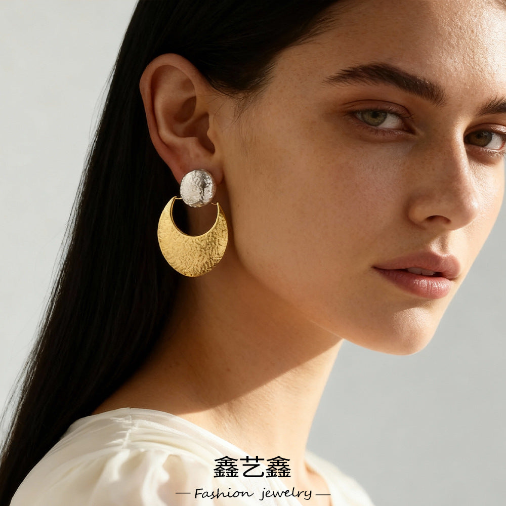 Close-up of woman wearing textured silver and gold crescent-shaped earrings, fashion jewelry from TycheLuck